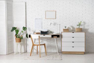 Kaliteli daktilo, kitap ve gazete ile aydınlık oturma odasında şık çalışma alanı