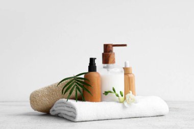 Kozmetik ürünler, banyo süngeri ve arka planda temiz havlu.