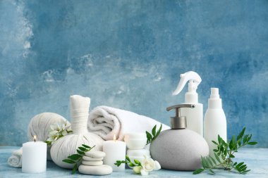 Yanan mumlar, bitki yaprakları ve grunge renk arkaplanındaki çiçeklerle spa kompozisyonu