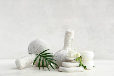 Hafif arkaplanda spa aksesuarları, kozmetik ürünleri, çiçek ve palmiye yaprağı olan kompozisyon