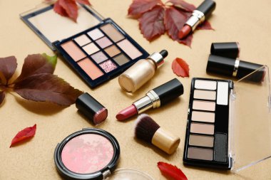 Renkli arka planda dekoratif kozmetik ve güzel sonbahar yapraklarıyla kompozisyon