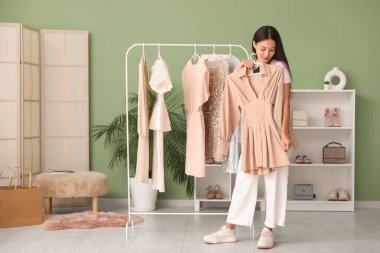 Elbise rafının yanındaki güzel genç kadın mağazada elbise seçiyor.