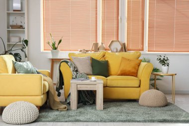 Rahat sarı kanepesi, koltuğu ve sehpası olan şık bir oda.