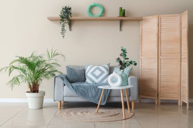 Oturma odasının içinde vazolar olan rahat bir kanepe ve kahve masası.