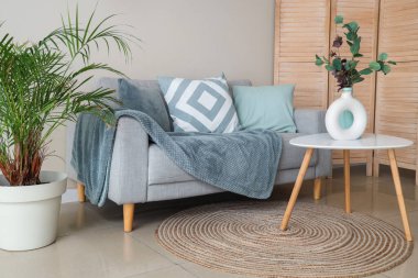 Oturma odasının içinde vazolar olan rahat bir kanepe ve kahve masası.