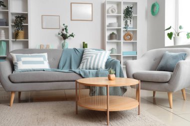 Oturma odasının iç tarafında rahat bir kanepe, koltuk ve sehpa.