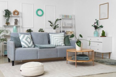 Konforlu kanepe, kahve masası ve oturma odasının iç tarafındaki bitkiler.