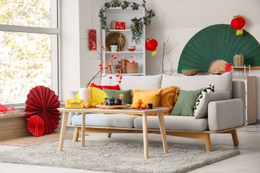 Çin Yeni Yıl kutlamaları için kanepe, masa ve dekorla aydınlık oturma odasının içinde.