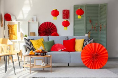 Çin Yeni Yıl kutlamaları için gri kanepe, masa ve dekorla aydınlık oturma odasının içinde.