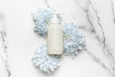 Güzel mavi kasımpatı çiçekleri ve beyaz arka planda bir şişe kozmetik ürünü.