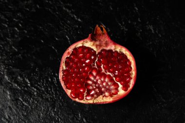 Lezzetli olgun narların yarısı siyah arka planda, yakın plan.