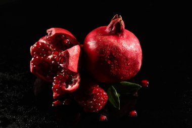 Siyah zemin üzerinde lezzetli olgun nar parçaları, yakın plan.