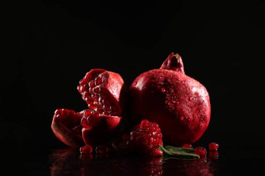Siyah zemin üzerinde olgun, lezzetli nar parçaları.