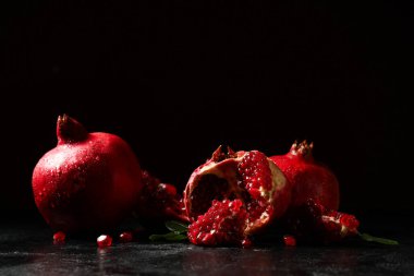 Siyah arka planda tohumları olan taze nar parçaları.