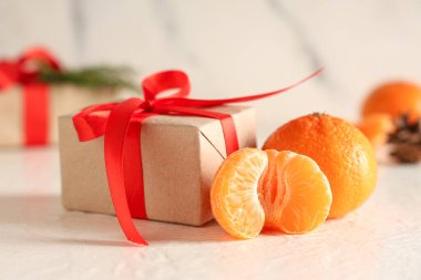 Tatlı mandalinalar, hediye kutuları beyaz masada, grunge duvarının yanında.