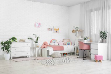 Yatak, çalışma masası ve çekmeceleri olan şık bir çocuk odası.