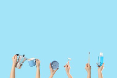 Kahve, çalar saat, yüz masajı aleti ve mavi arka planda diş fırçası olan kadın elleri. Günaydın konsept.