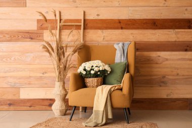 Koltuk, güzel beyaz kasımpatılar ve tahta duvarın yanındaki merdiven.