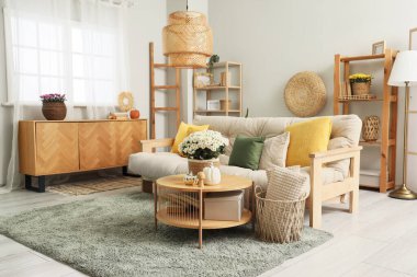 Rahat kanepesi ve kahve masasında kasımpatı çiçekleri olan modern oturma odasının içinde.