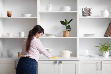 Mutfakta farklı tabakları olan rafların yanındaki güzel genç kadın.