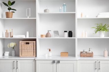 Banyoda banyo malzemeleri ve kozmetik ürünleri olan beyaz raf ünitesi.