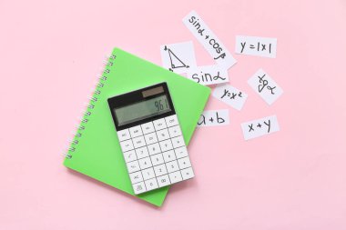 Not defteri, hesap makinesi, pembe arkaplan üzerinde farklı matematik formülleri ve denklemleri