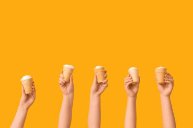 Sarı arka planda waffle bardaklarında tatlı dondurmalı kadın elleri