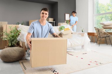 Taşındığı gün karısı ve kutusuyla odada olan genç bir adam.