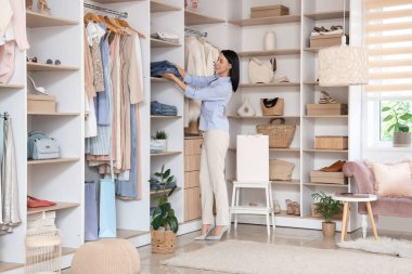 Kadın satıcı elbise mağazasındaki raftan katlanmış kot pantolon alıyor.