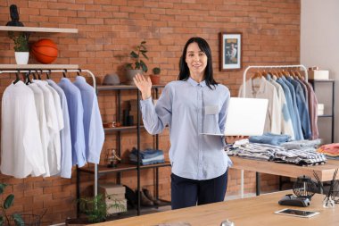 Erkek giyim mağazasında dizüstü bilgisayarı olan bir kadın satıcı.