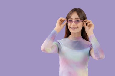 Mor arka planda güneş gözlüklü şık bir genç kadın.