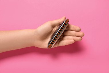 Pembe arka planda mızıkalı kadın eli, yakın plan.