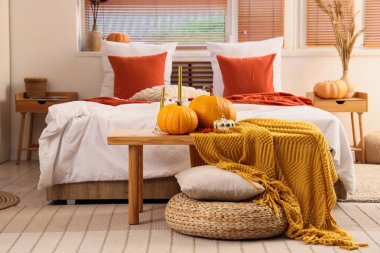 Yatak odasının yanındaki sehpanın üstünde balkabakları ve mumlar.