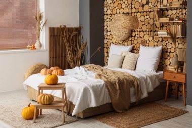 Yatak, balkabağı ve komodinli rahat bir yatak odası.