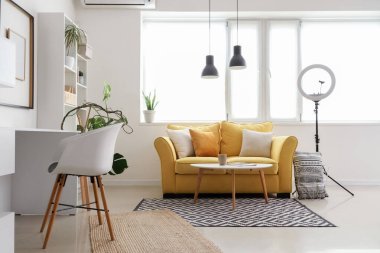 Podcaster 'ın stüdyosunun içinde kanepe, işyeri ve raf ünitesi var.