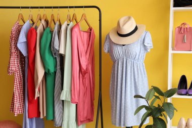 Manken ve askılar, soyunma odasındaki sarı duvarın yanında.