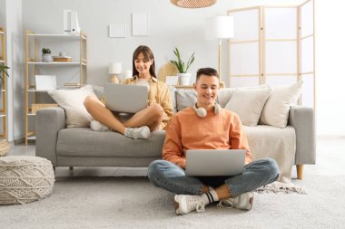 Evde dizüstü bilgisayar kullanan genç çift.