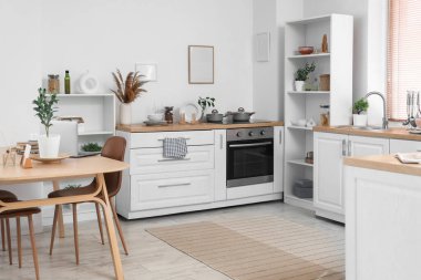 Mutfağın içinde yemek masası, tezgah ve bitkiler var.