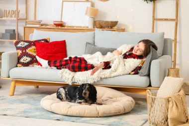 Sıcak battaniyeli küçük bir çocuk ve evdeki kanepede uzanmış tatlı bir cocker spanyel.