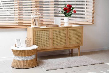 Oturma odasındaki sehpanın yanındaki çekmecede kırmızı yıldız çiçeği olan vazo.