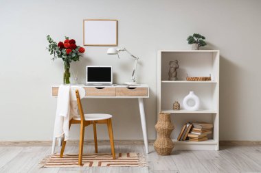 İş yerindeki vazoda Dahlia çiçekleri dizüstü bilgisayarın yanında ve odada lamba.