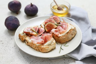 Beyaz arka planda prosciutto ve ricotta peynirli lezzetli incirli bruschetta tabağı.