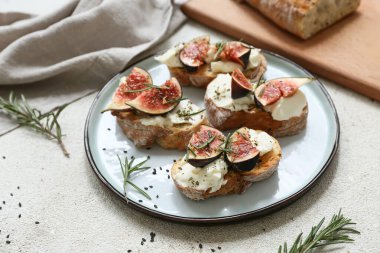 Beyaz arka planda ricotta peynirli ve biberiyeli lezzetli incirli bruschetta tabağı.