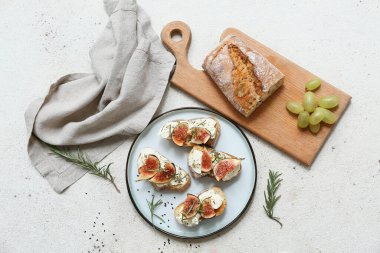 Beyaz zemin üzerinde ricotta peyniri ve biberiyeli lezzetli incirli bruschetta tabağı.