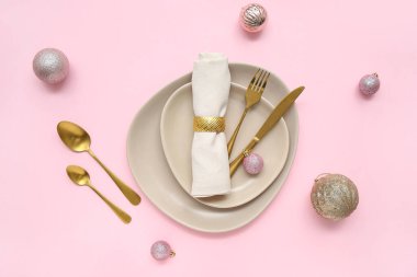 Pembe arka planda Noel topları olan güzel bir masa.