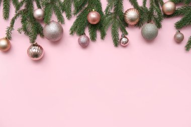 Pembe arka planda Noel topları ve köknar dallarıyla kompozisyon