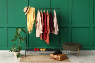 Odada yeşil duvarın yanında giysilerle dizilin.