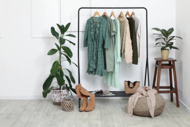 Soyunma odasındaki beyaz duvarın yanında giysilerle dizilin.