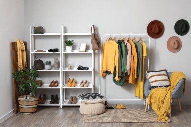 Giysileri, koltuğu ve raf ünitesi olan soyunma odasının içinde.