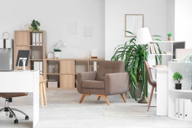 Masaları, koltukları ve bitkileri olan ışık ofisinin içi